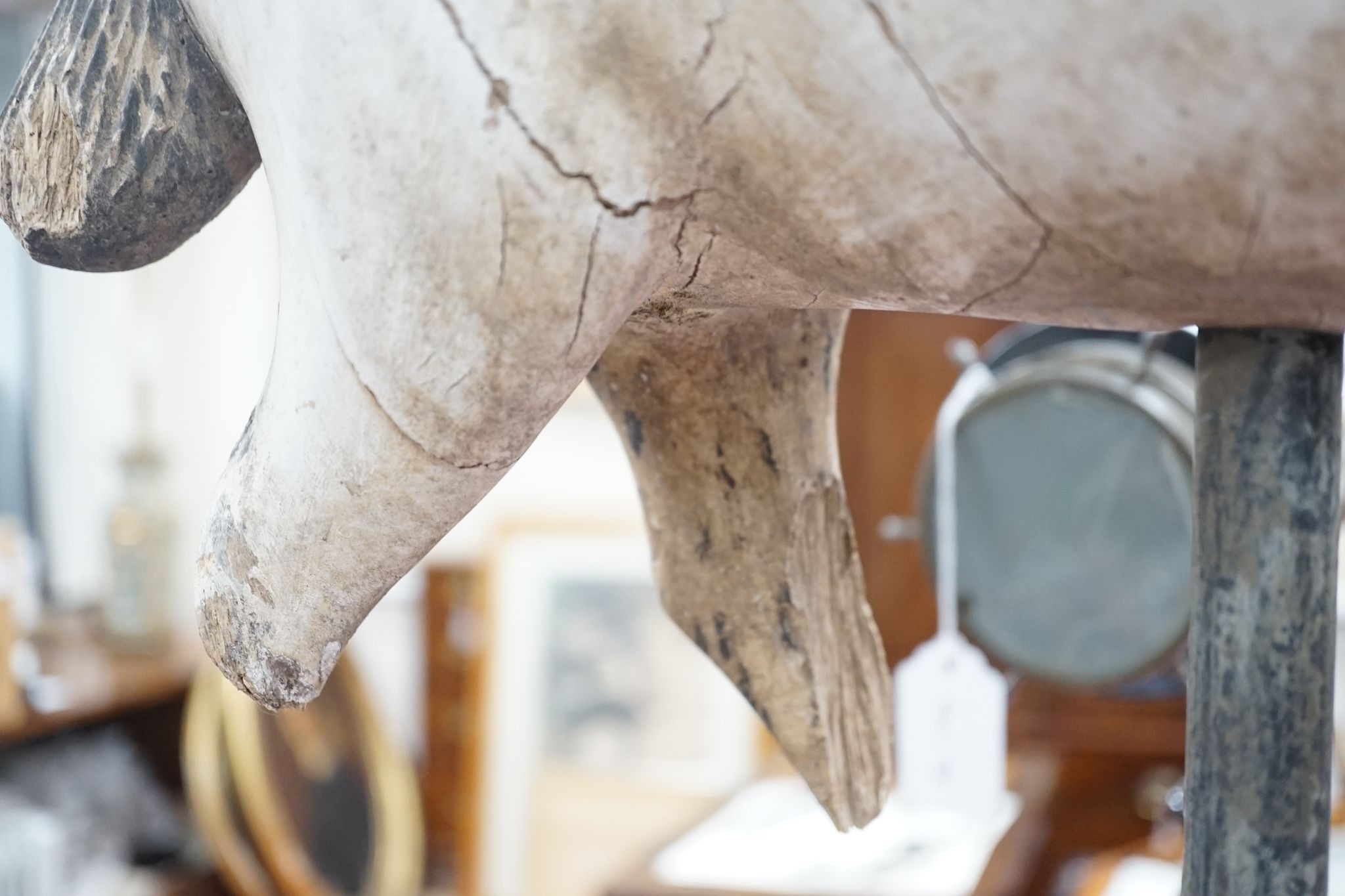 A carved and painted wood model of a goat, with distressed paint, on stand. 66cm